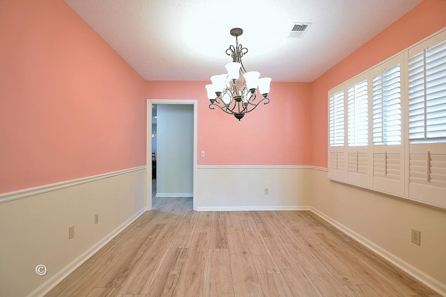 empty room featuring light hardwood / wood-style floors and a chandelier