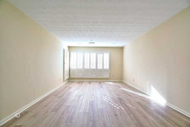 spare room with a textured ceiling and light wood-type flooring