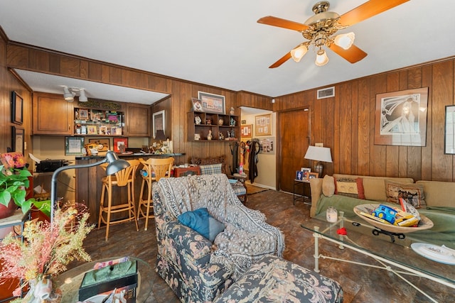 living room with ceiling fan and wood walls