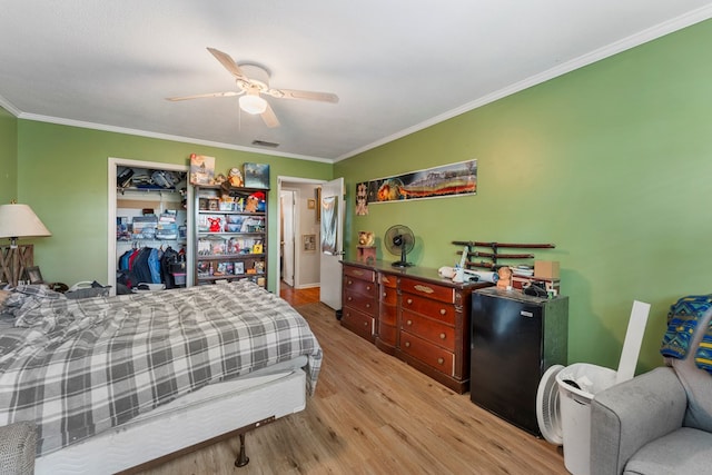 bedroom featuring ceiling fan, light wood-type flooring, ornamental molding, and a closet