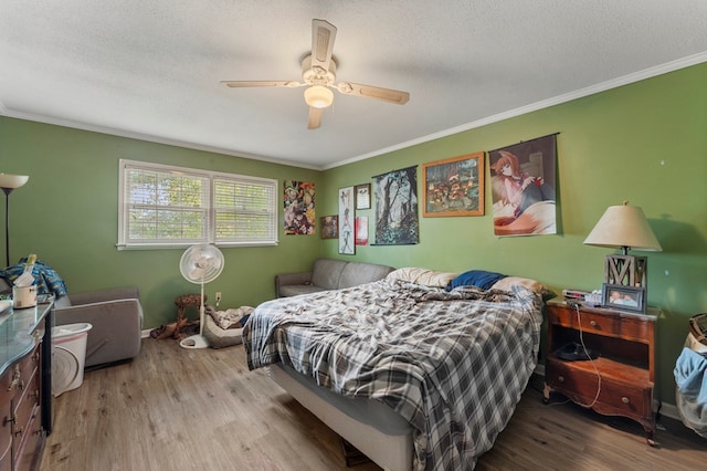 bedroom featuring ceiling fan, ornamental molding, a textured ceiling, and light wood-type flooring