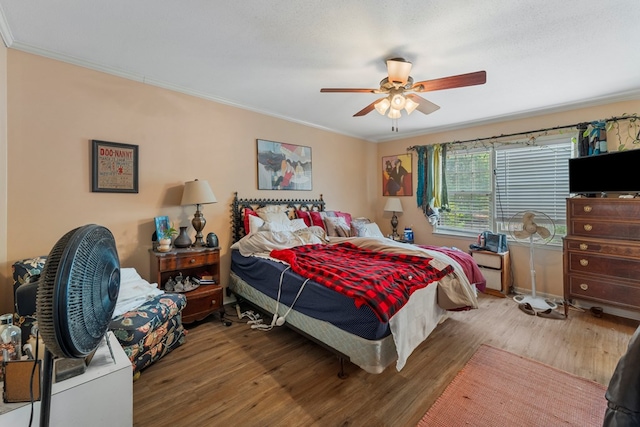 bedroom featuring hardwood / wood-style flooring, ceiling fan, and crown molding