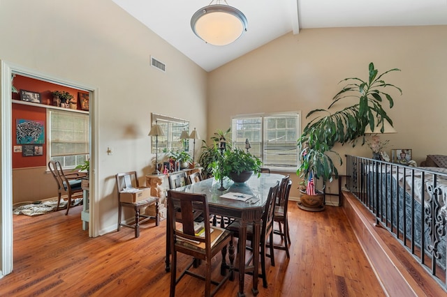 dining room featuring beam ceiling, hardwood / wood-style floors, and high vaulted ceiling