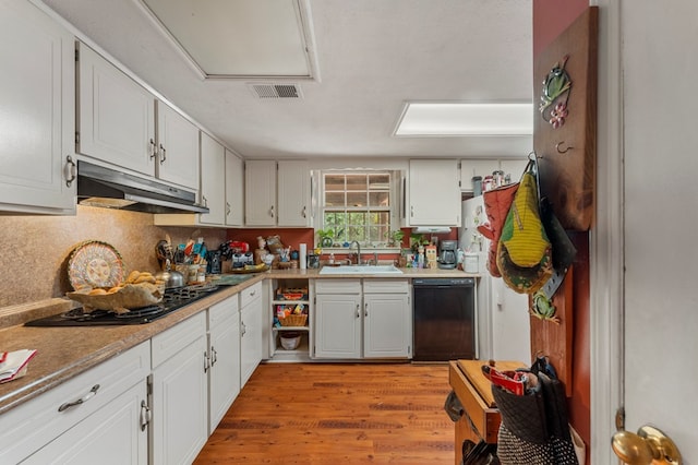 kitchen with white cabinetry, sink, decorative backsplash, black appliances, and light wood-type flooring