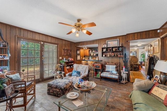 living room featuring a textured ceiling, crown molding, ceiling fan, and wooden walls