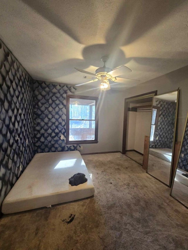 unfurnished bedroom featuring carpet floors, a textured ceiling, and ceiling fan