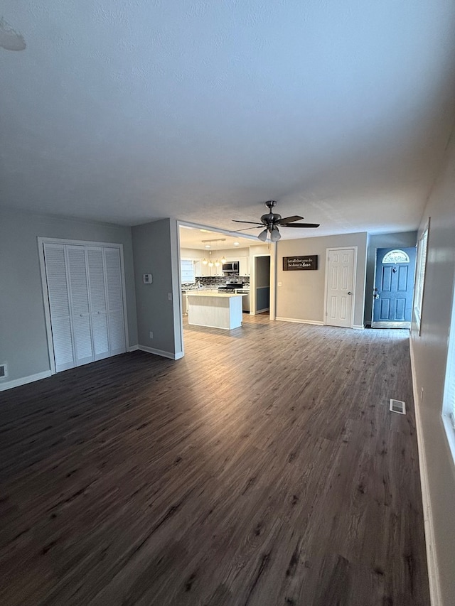 unfurnished living room with dark wood-type flooring and ceiling fan