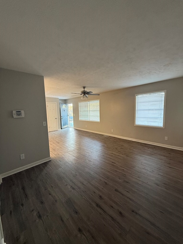 unfurnished living room with dark wood-type flooring and ceiling fan