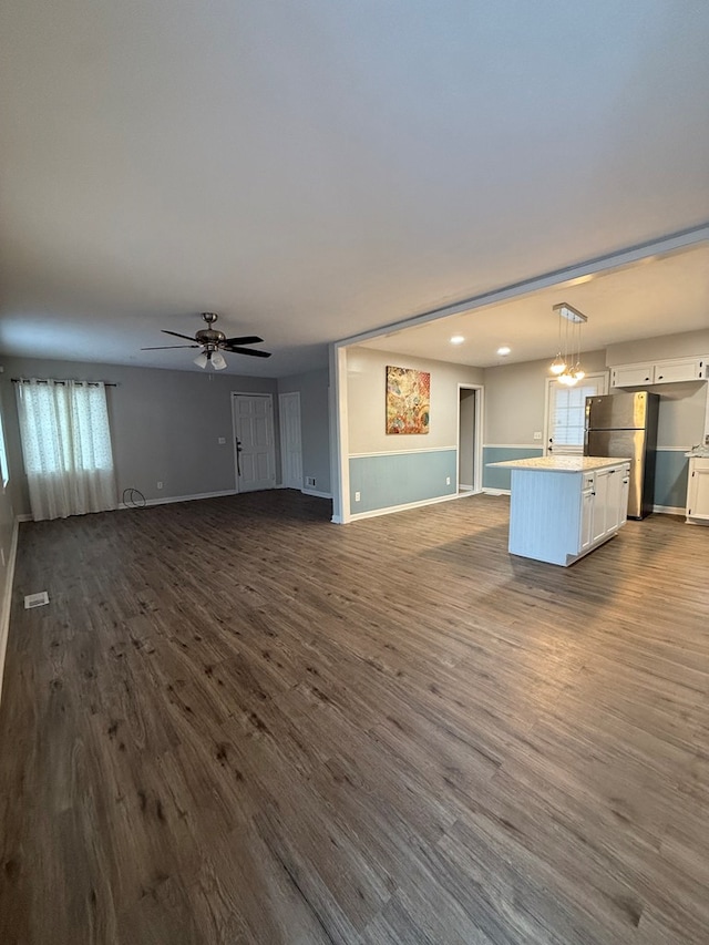 unfurnished living room with dark hardwood / wood-style flooring, plenty of natural light, and ceiling fan