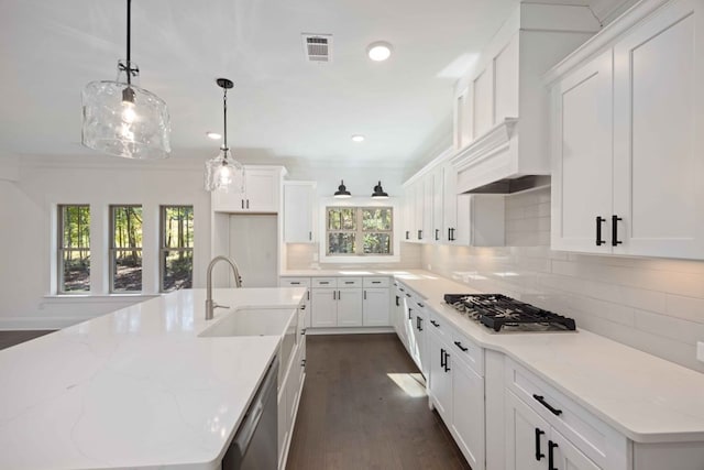 kitchen with a kitchen island with sink, white cabinets, dark hardwood / wood-style floors, light stone countertops, and appliances with stainless steel finishes