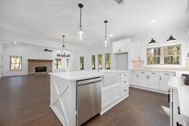 kitchen with stainless steel dishwasher, plenty of natural light, white cabinets, and a fireplace