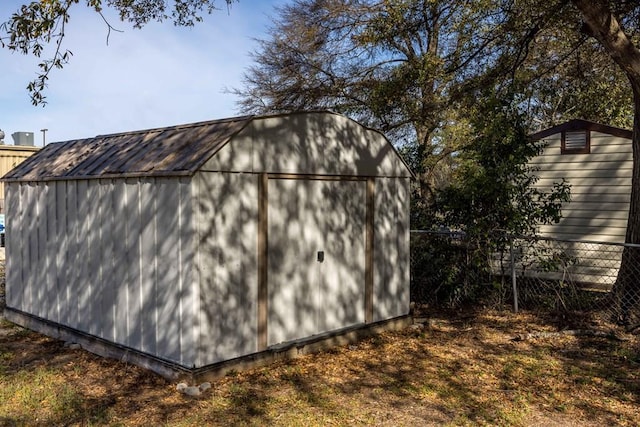 view of property exterior featuring metal roof, a storage shed, an outdoor structure, and fence