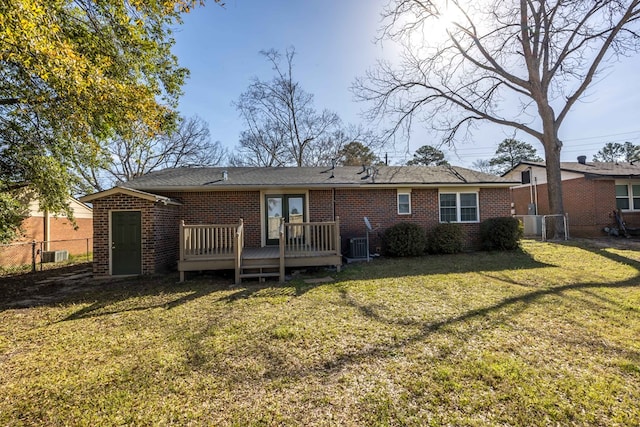 rear view of property with fence, french doors, a deck, a lawn, and brick siding