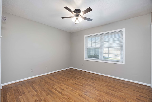 spare room featuring wood finished floors, baseboards, and ceiling fan