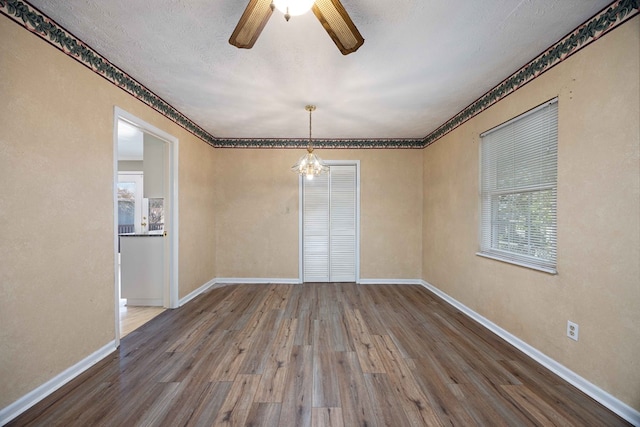 unfurnished room featuring ceiling fan with notable chandelier, wood finished floors, baseboards, and a textured ceiling