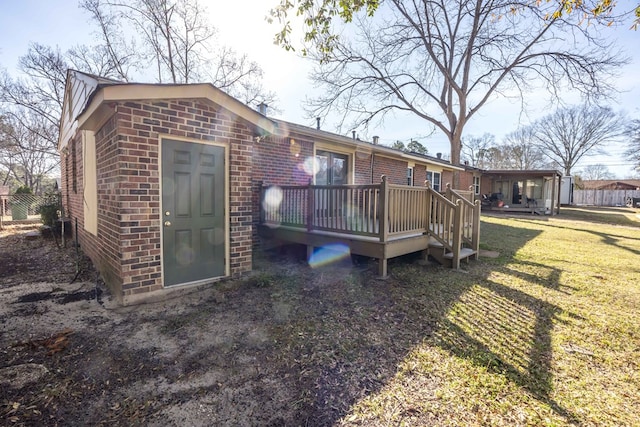 back of house with a lawn, brick siding, and a wooden deck