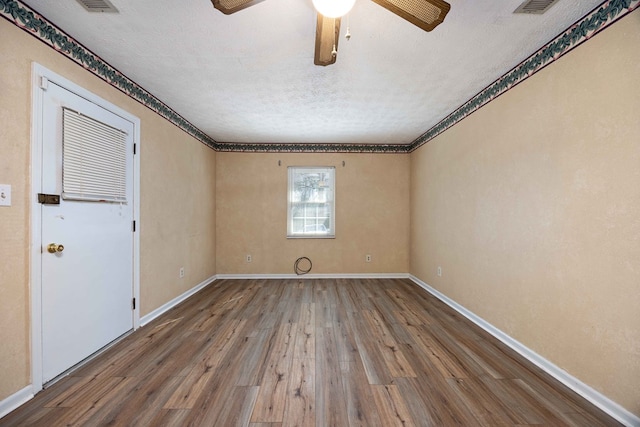 empty room with ceiling fan, baseboards, a textured ceiling, and wood finished floors