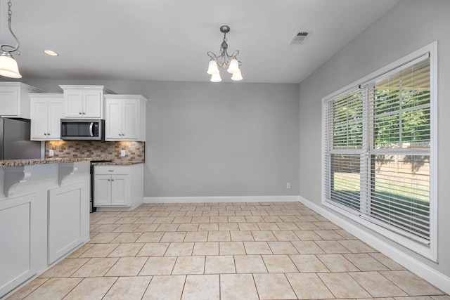 kitchen featuring white cabinets, appliances with stainless steel finishes, a healthy amount of sunlight, and a notable chandelier