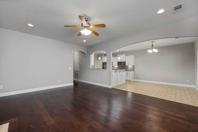 unfurnished living room with hardwood / wood-style floors and ceiling fan with notable chandelier