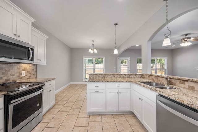 kitchen featuring tasteful backsplash, stainless steel appliances, sink, white cabinets, and hanging light fixtures