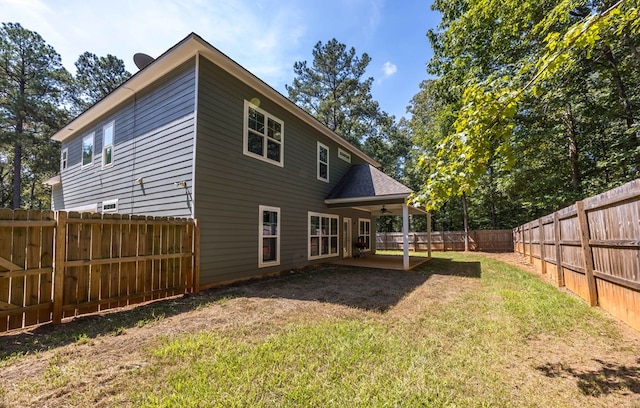 back of property with ceiling fan and a yard