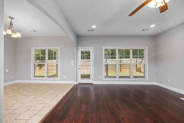 unfurnished room featuring ceiling fan with notable chandelier and hardwood / wood-style flooring