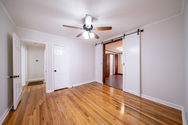 1729 41st St, Columbus, GA 31904 - unfurnished bedroom with light wood finished floors, crown molding, ceiling fan, a barn door, and baseboards