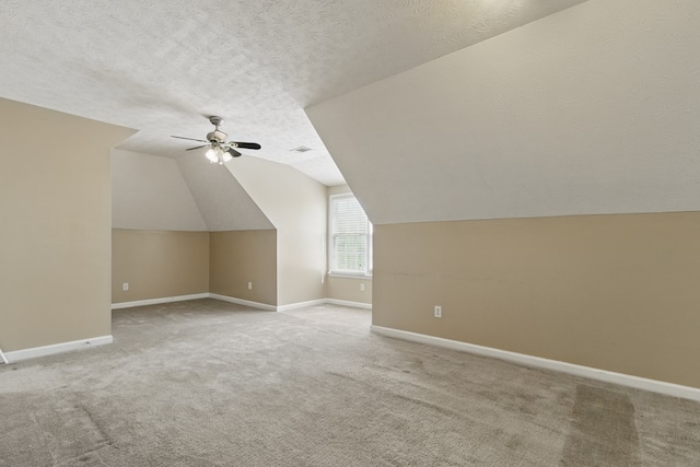 additional living space featuring lofted ceiling, visible vents, baseboards, carpet flooring, and ceiling fan