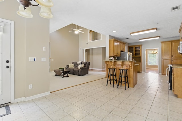 kitchen with a kitchen breakfast bar, ceiling fan with notable chandelier, a peninsula, visible vents, and freestanding refrigerator