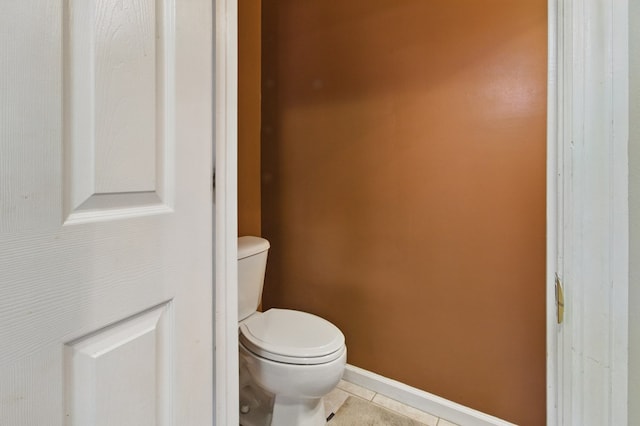 bathroom featuring baseboards, tile patterned flooring, and toilet