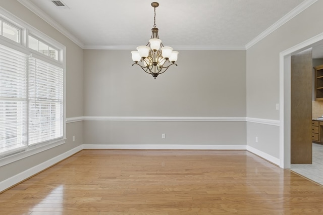 empty room with light wood finished floors, baseboards, a notable chandelier, and ornamental molding