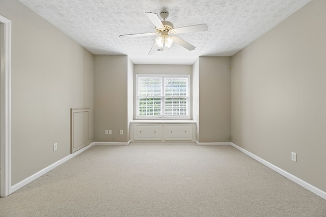 unfurnished room with light colored carpet, baseboards, and a textured ceiling