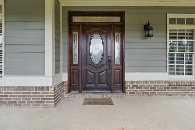 property entrance with a porch and brick siding