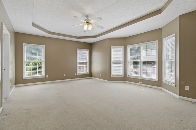 spare room featuring baseboards, a tray ceiling, ceiling fan, and light colored carpet