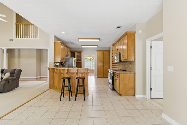 kitchen featuring a kitchen breakfast bar, stainless steel appliances, visible vents, decorative backsplash, and a peninsula