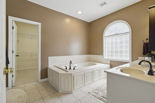 bathroom with a spacious closet, tile patterned floors, visible vents, vanity, and a garden tub
