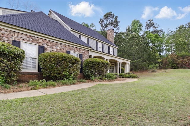 view of side of property featuring stone siding, a lawn, a chimney, and a high end roof