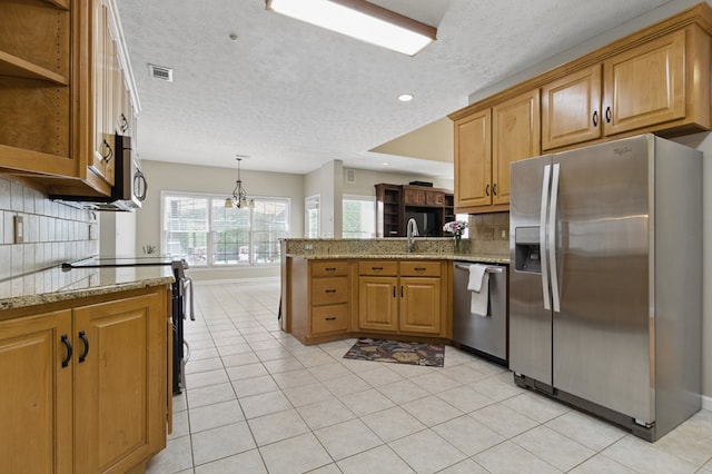 kitchen with backsplash, visible vents, a peninsula, a textured ceiling, and appliances with stainless steel finishes
