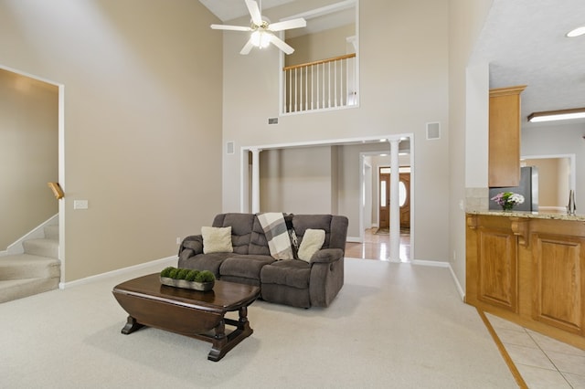 living room featuring stairway, a towering ceiling, visible vents, a ceiling fan, and baseboards
