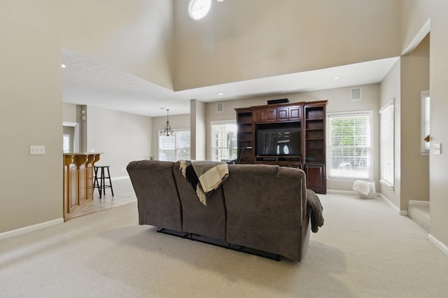 living area featuring visible vents, light carpet, baseboards, and a chandelier