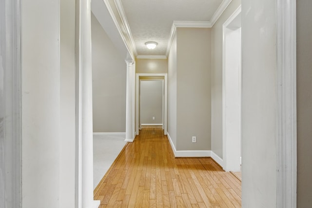 hallway with light wood-type flooring, baseboards, and ornamental molding