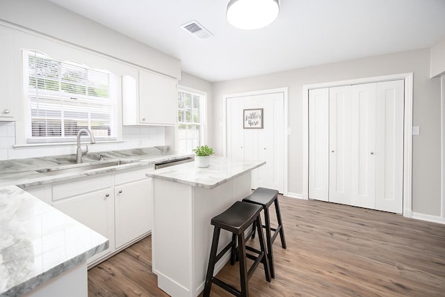 8085 Ga Highway 0219, Hamilton, GA 31811 - kitchen with wood finished floors, a kitchen breakfast bar, white cabinets, a center island, and light stone countertops