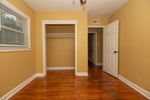 unfurnished bedroom with a closet and dark wood-type flooring