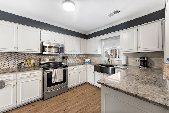 kitchen featuring sink, white cabinetry, stainless steel appliances, light stone countertops, and backsplash