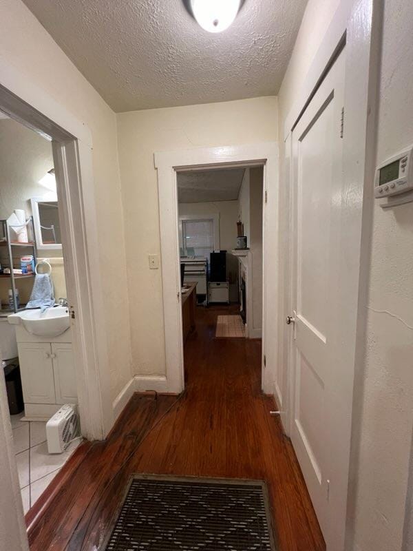 corridor with a textured ceiling and dark wood-type flooring