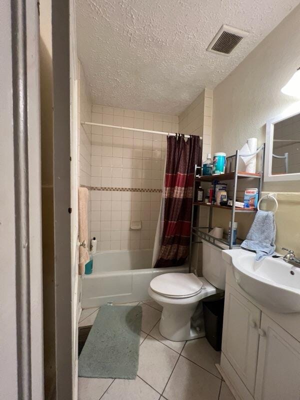 full bathroom with tile patterned flooring, vanity, toilet, and a textured ceiling