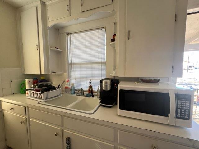 kitchen with tasteful backsplash, white cabinetry, a wealth of natural light, and sink