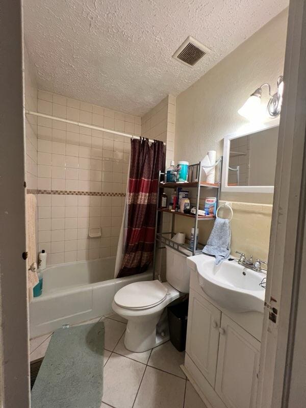 full bathroom featuring tile patterned floors, vanity, a textured ceiling, and toilet