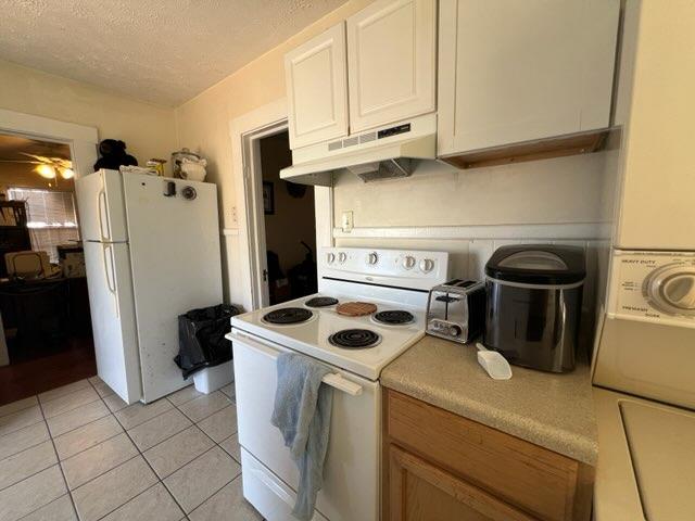 kitchen featuring white cabinets, a textured ceiling, white appliances, and light tile patterned flooring