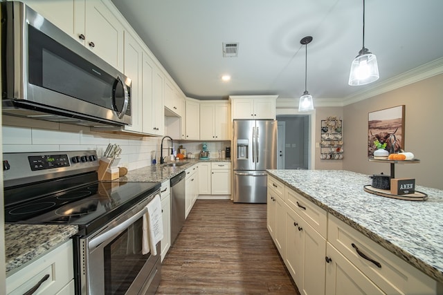 kitchen featuring appliances with stainless steel finishes, decorative light fixtures, sink, white cabinets, and light stone countertops